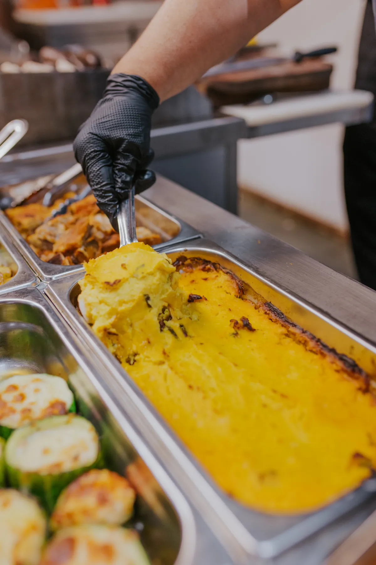 Pastel de choclo dorado y zapallitos gratinados en la estación de calientes