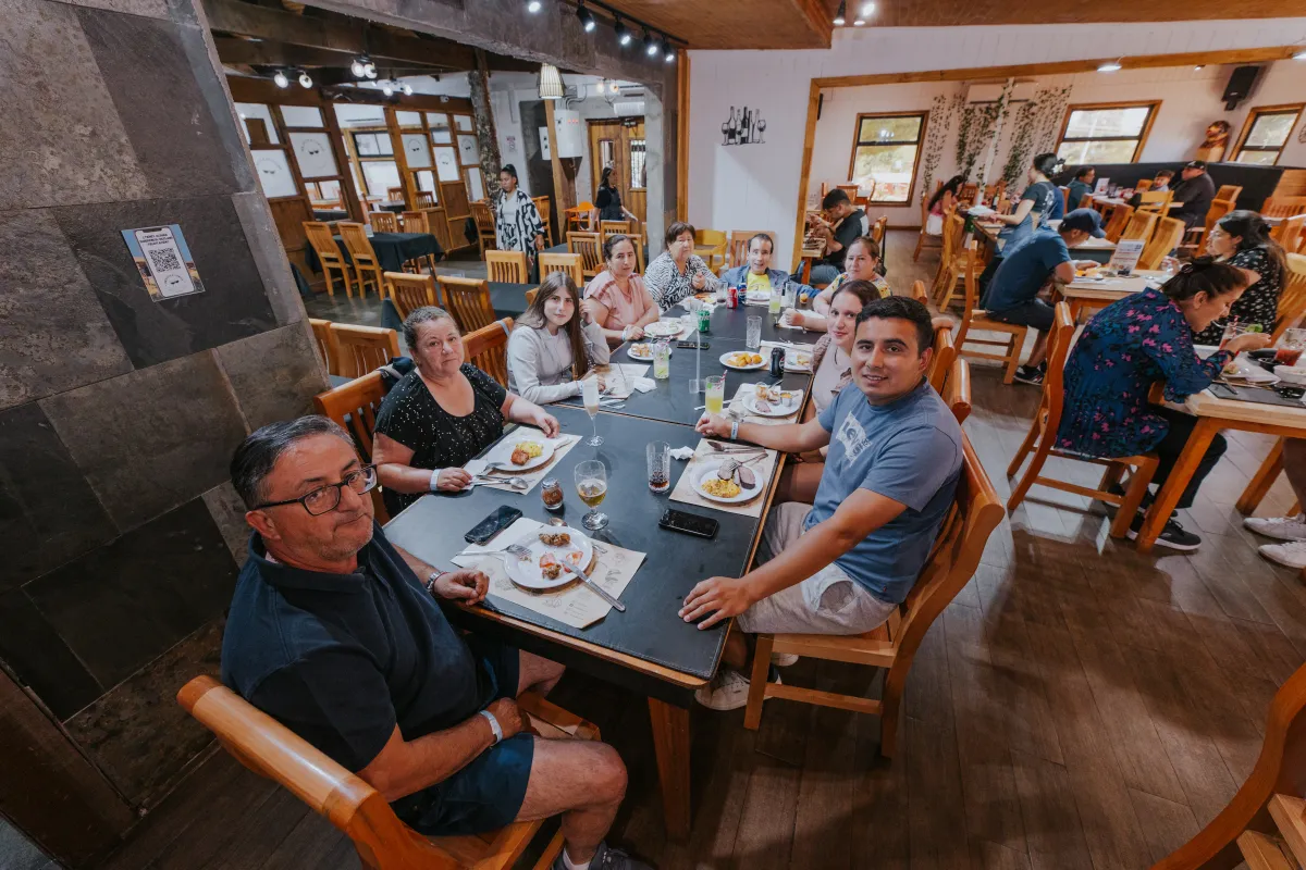 Familia numerosa sonriente compartiendo almuerzo en una mesa larga